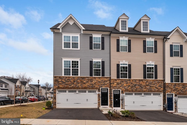 view of property with a residential view, stone siding, an attached garage, and driveway