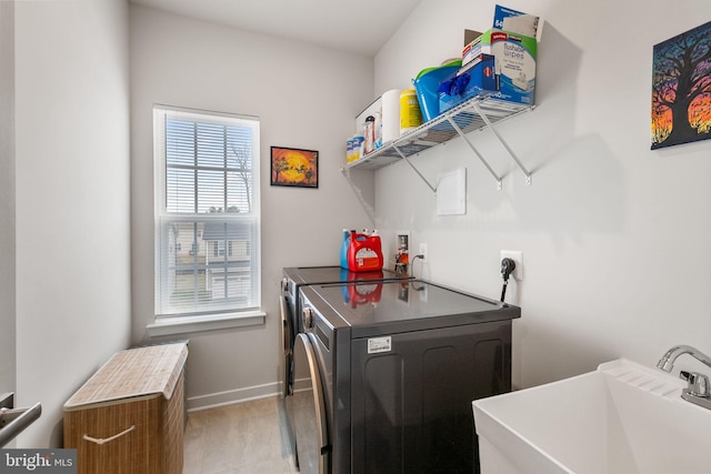 laundry room featuring baseboards, laundry area, light tile patterned flooring, a sink, and independent washer and dryer