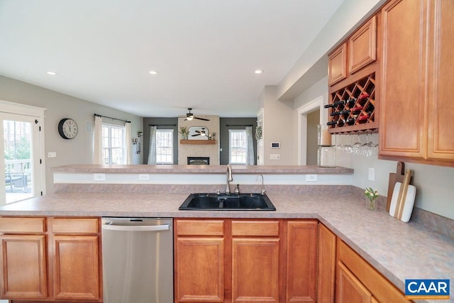 kitchen featuring a glass covered fireplace, a healthy amount of sunlight, dishwasher, and a sink