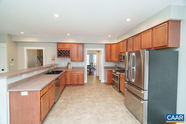 kitchen with a sink, recessed lighting, stainless steel appliances, a peninsula, and light countertops