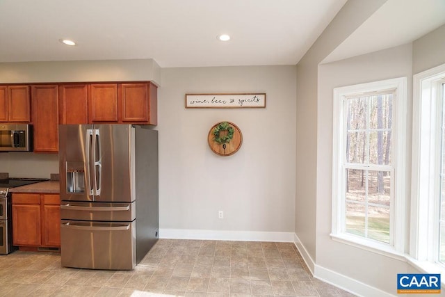 kitchen with brown cabinetry, stainless steel appliances, and a wealth of natural light