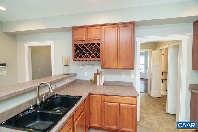 kitchen with a sink, recessed lighting, brown cabinetry, and light countertops