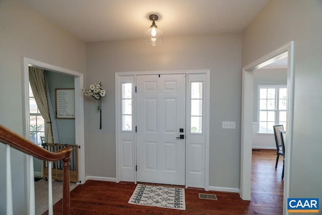 entryway with visible vents, baseboards, dark wood finished floors, and stairway