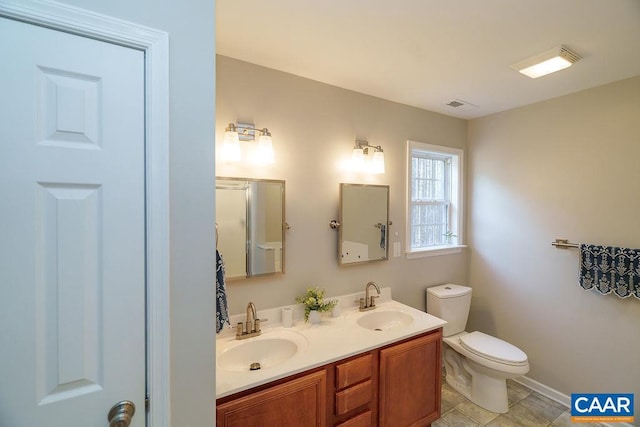 bathroom featuring a sink, visible vents, toilet, and double vanity