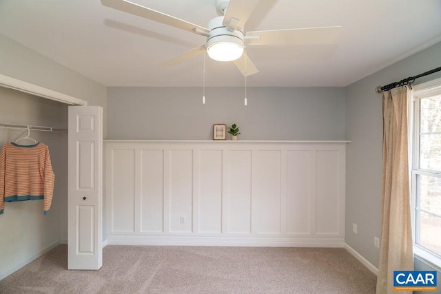 unfurnished bedroom with a closet, light colored carpet, and a ceiling fan