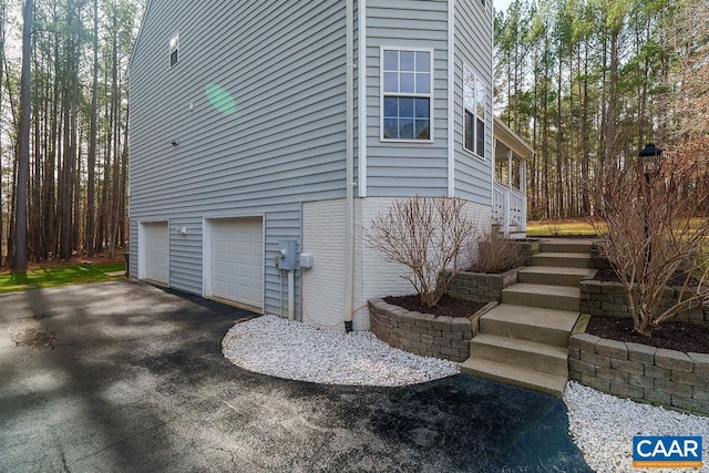 view of property exterior with an attached garage and driveway