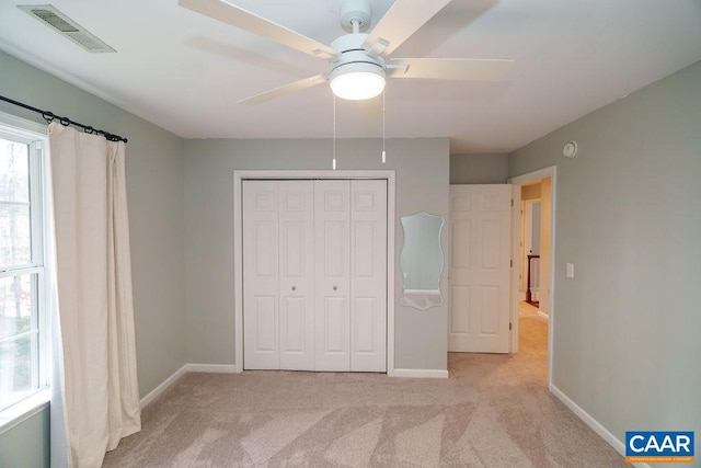 unfurnished bedroom featuring light carpet, visible vents, a closet, and baseboards