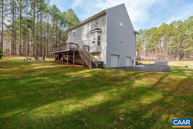 rear view of property with aphalt driveway, a wooden deck, stairs, a lawn, and a garage