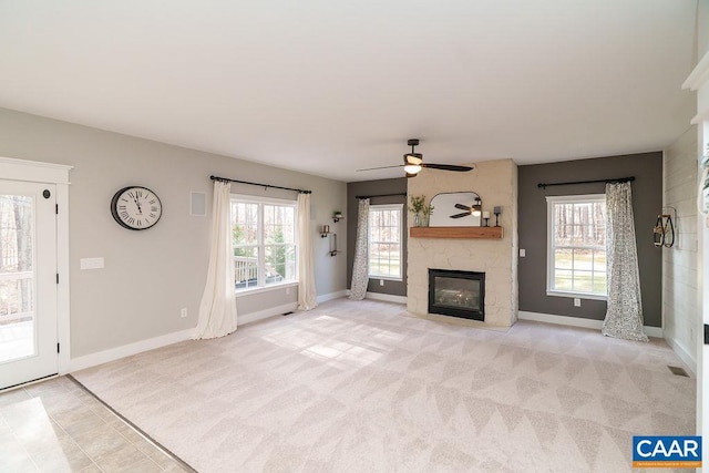 unfurnished living room with a high end fireplace, a healthy amount of sunlight, light carpet, and baseboards