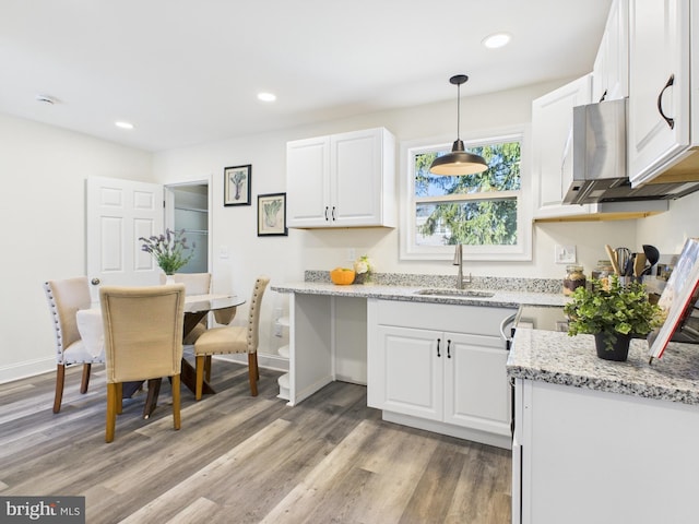 kitchen with recessed lighting, white cabinets, light wood-type flooring, and a sink