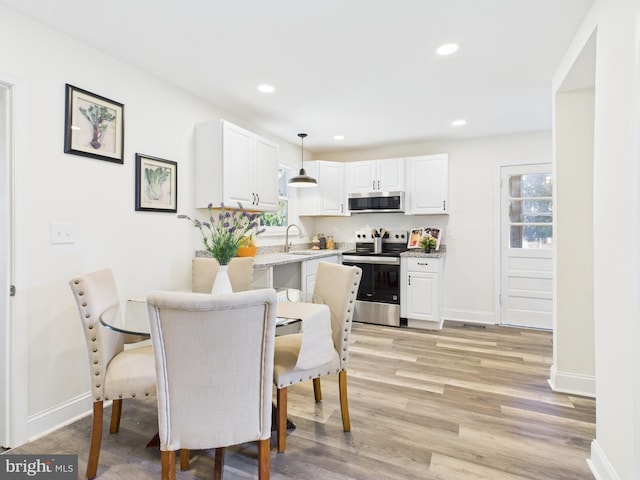 dining space featuring light wood-style flooring, recessed lighting, a healthy amount of sunlight, and baseboards