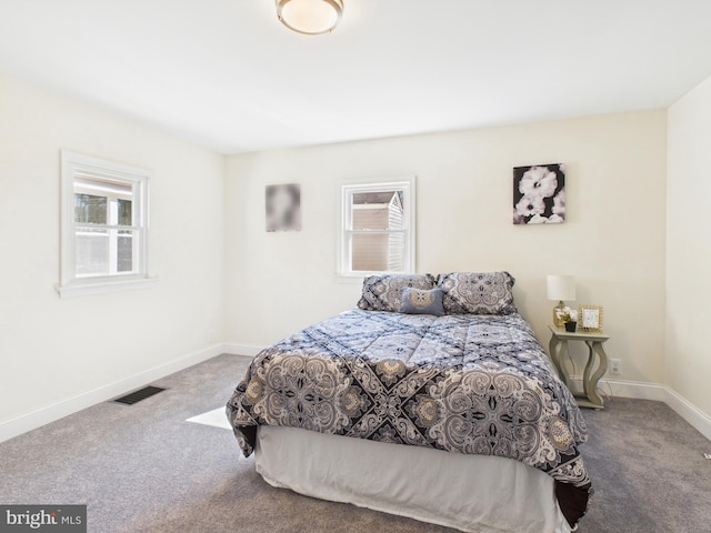 carpeted bedroom featuring visible vents, multiple windows, and baseboards