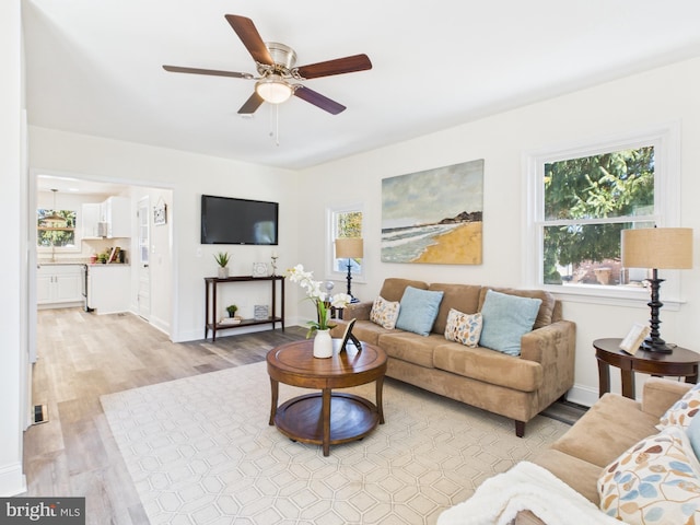 living area featuring visible vents, ceiling fan, baseboards, and light wood-style floors