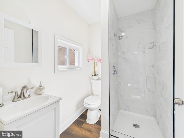 bathroom with a marble finish shower, baseboards, toilet, wood finished floors, and vanity