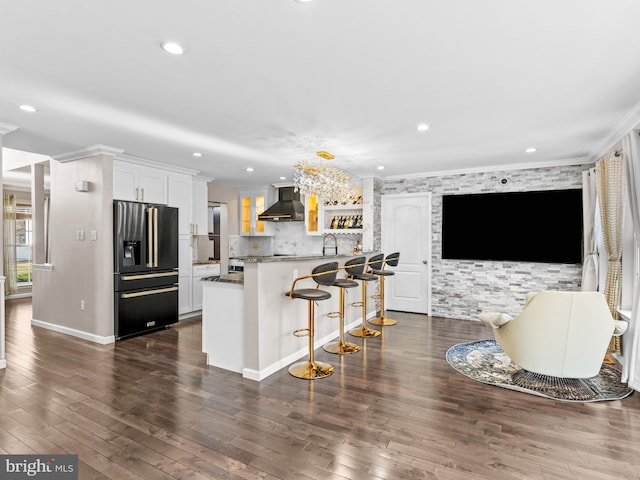 kitchen featuring a sink, dark wood-type flooring, crown molding, wall chimney exhaust hood, and black refrigerator with ice dispenser