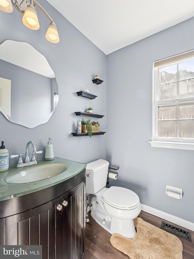 bathroom featuring visible vents, toilet, wood finished floors, baseboards, and vanity