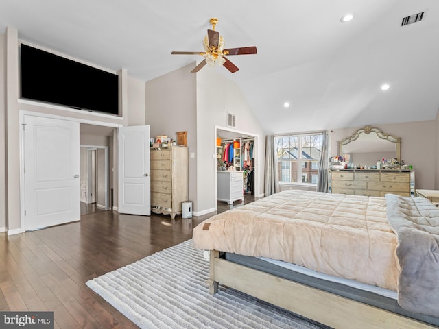 bedroom featuring visible vents, dark wood-style floors, baseboards, a spacious closet, and vaulted ceiling