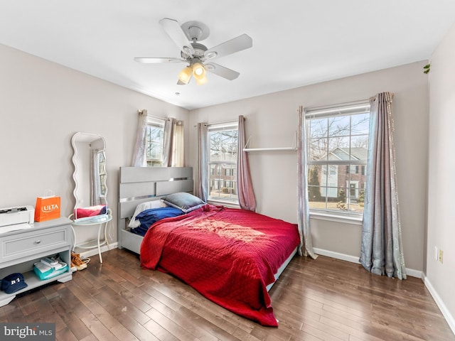 bedroom with multiple windows, wood-type flooring, baseboards, and a ceiling fan