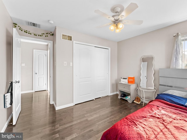 bedroom with a closet, visible vents, baseboards, and wood finished floors