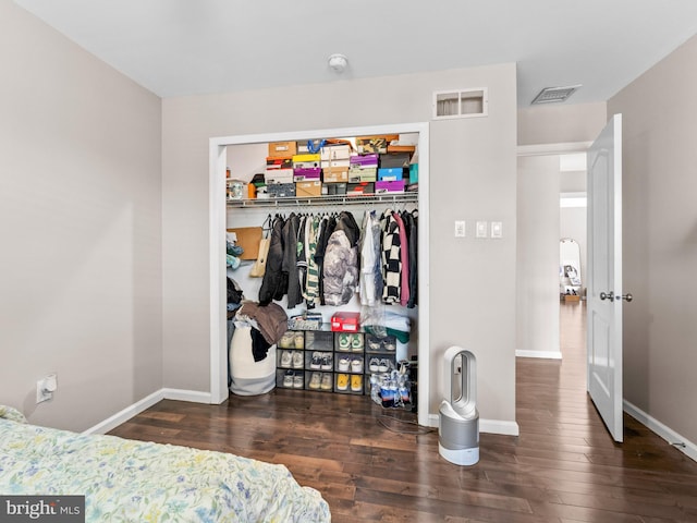 bedroom with wood finished floors, visible vents, a closet, and baseboards