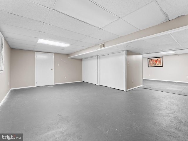 finished below grade area featuring a paneled ceiling, visible vents, and baseboards