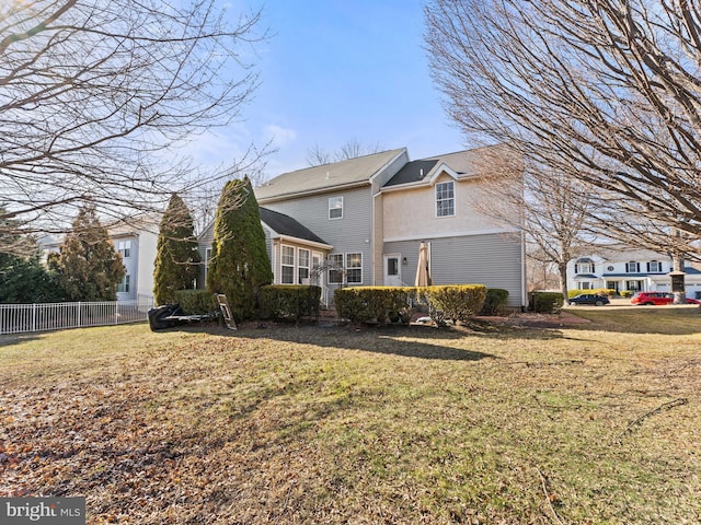 back of house featuring a lawn and fence