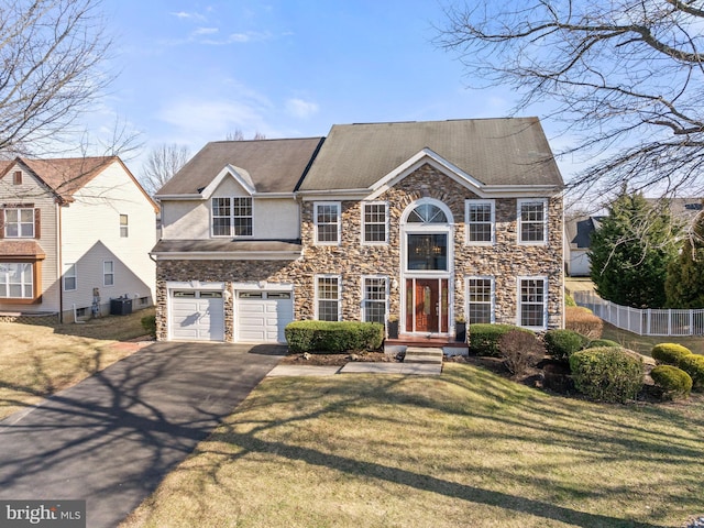 view of front of home featuring a front lawn, fence, aphalt driveway, stucco siding, and an attached garage