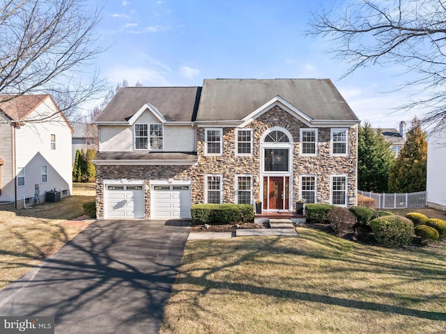 view of front of house with aphalt driveway, an attached garage, a front lawn, and fence