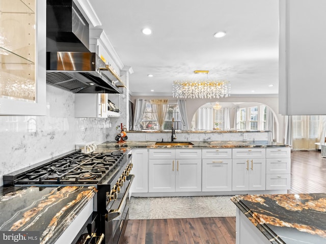 kitchen with high end range, ornamental molding, a sink, wood-type flooring, and wall chimney exhaust hood