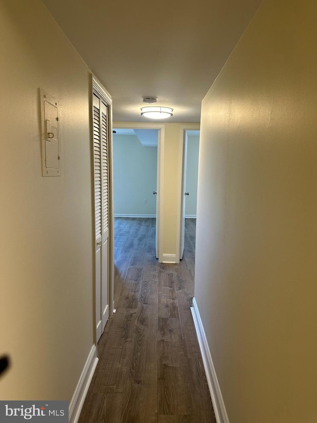 hall featuring baseboards and dark wood-style flooring