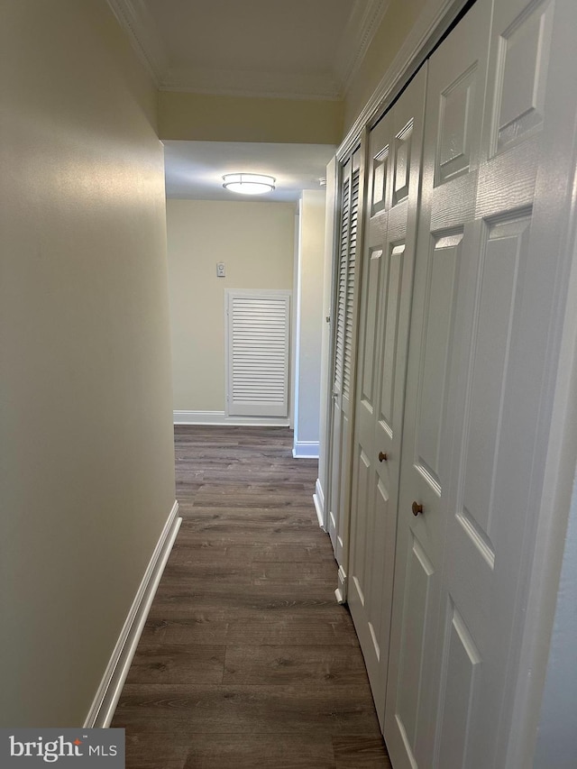 corridor with crown molding, dark wood-type flooring, and baseboards