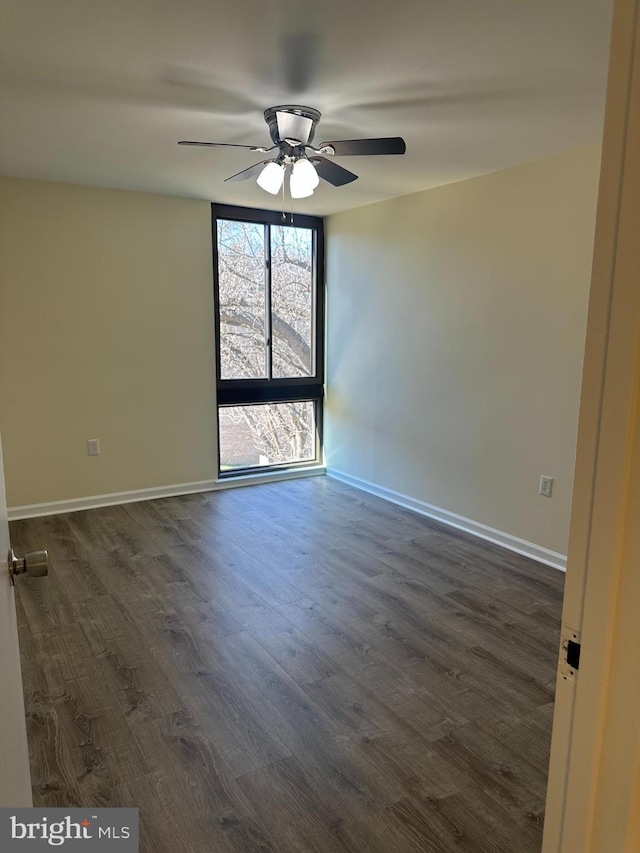 unfurnished room featuring baseboards, dark wood-type flooring, and ceiling fan