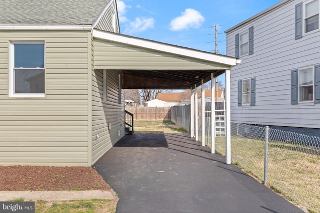 view of parking with an attached carport and fence