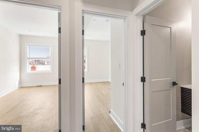 corridor featuring light wood-style flooring and baseboards