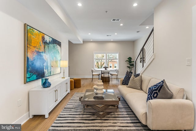 living room featuring recessed lighting, visible vents, light wood-style flooring, and stairway