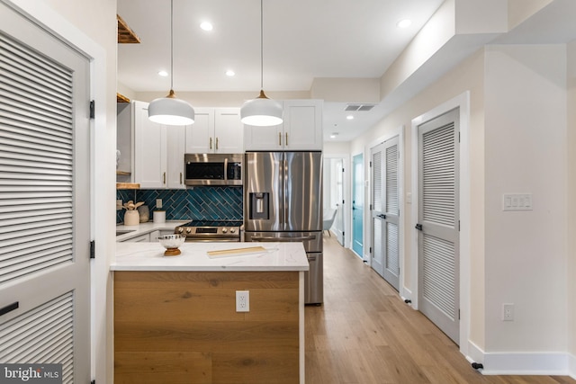 kitchen featuring light wood finished floors, visible vents, tasteful backsplash, stainless steel appliances, and white cabinetry