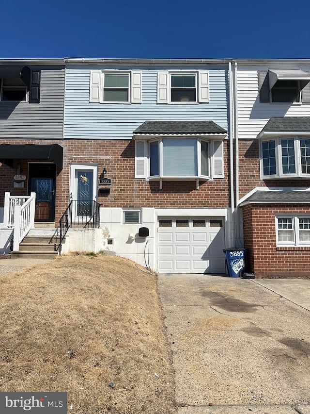 townhome / multi-family property featuring aphalt driveway, brick siding, and a garage