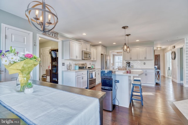 kitchen featuring dark wood finished floors, a breakfast bar, light countertops, appliances with stainless steel finishes, and white cabinets