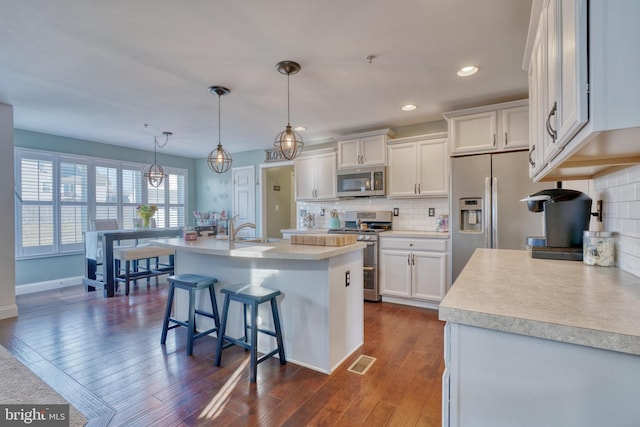 kitchen featuring visible vents, dark wood-style flooring, stainless steel appliances, light countertops, and white cabinetry