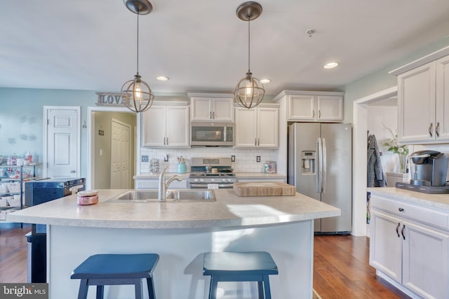 kitchen featuring a sink, white cabinets, a kitchen bar, and stainless steel appliances