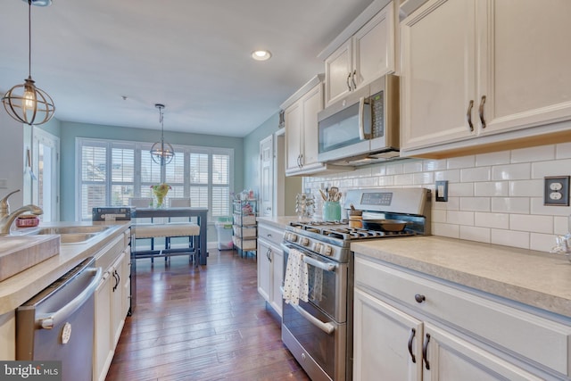 kitchen with dark wood-type flooring, a sink, stainless steel appliances, white cabinets, and decorative backsplash