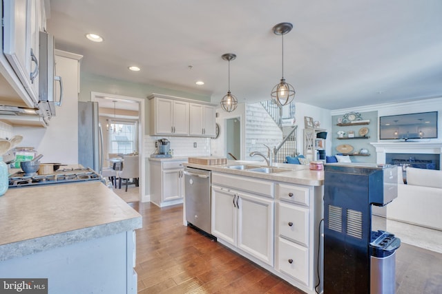 kitchen with a sink, stainless steel appliances, wood finished floors, and white cabinetry