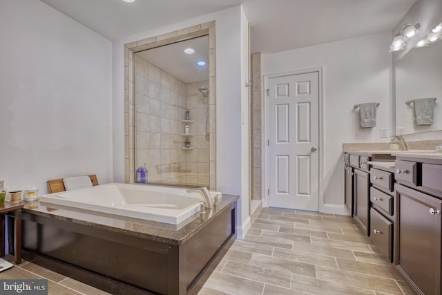 full bath featuring vanity, baseboards, wood finish floors, a stall shower, and a garden tub