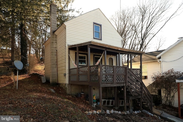 back of property with stairs and a chimney