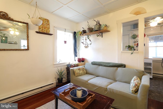 living area featuring baseboard heating, wood finished floors, and a ceiling fan