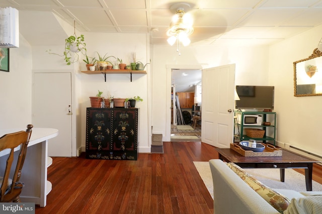 living room featuring baseboard heating, wood finished floors, and a ceiling fan