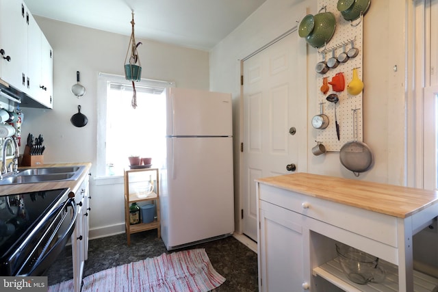 kitchen featuring a sink, black range with electric cooktop, white cabinetry, freestanding refrigerator, and wooden counters