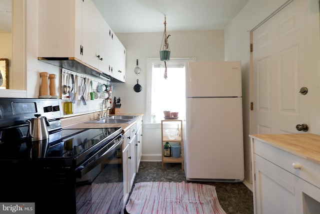 kitchen with freestanding refrigerator, a sink, light countertops, electric stove, and white cabinetry