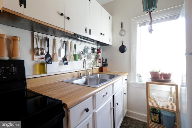 kitchen featuring a sink, plenty of natural light, black range with electric stovetop, and light countertops