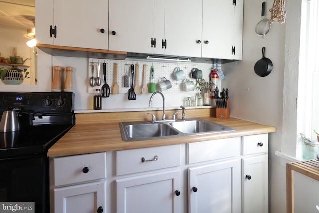 kitchen featuring a sink, black range with electric cooktop, and white cabinetry